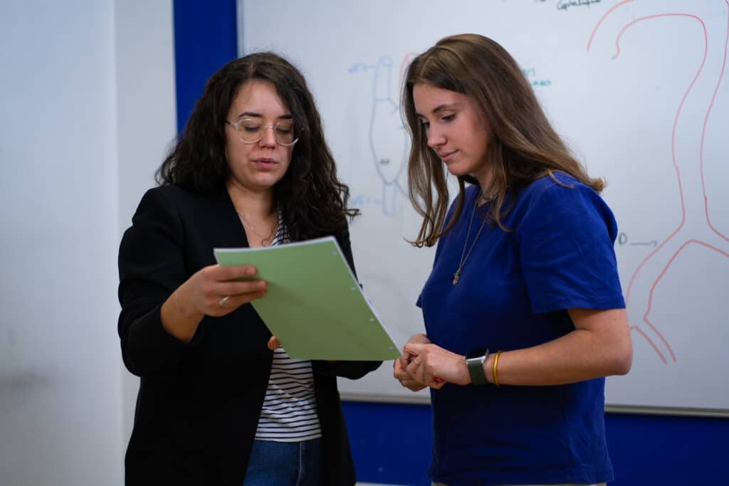 Enseignante et étudiante échangeant sur un document dans une salle de cours de Bersot Formation à Besançon